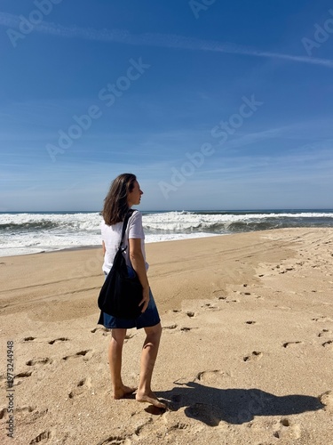 A summer stroll along the Atlantic Ocean beach. The model is a 50-year-old woman.