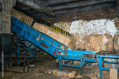 Foto Blue conveyor belt moves bundles of recycled cardboard and paper up a slope at a recycling plant