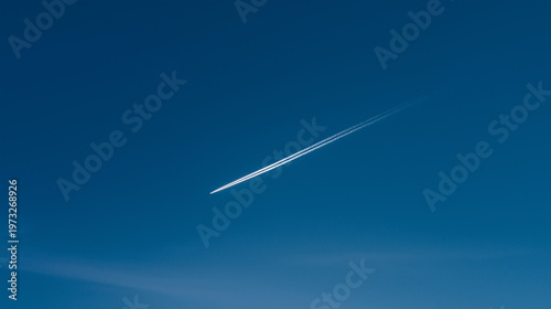 Contrail in the Sky: A single, elongated contrail gracefully streaks across a vibrant, expansive blue sky, offering a sense of depth and vastness.