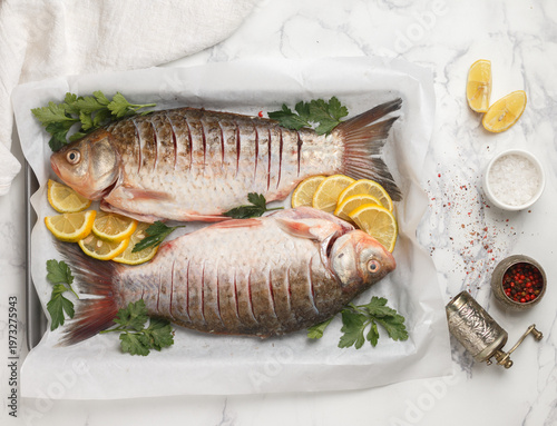 Two fresh raw crucian carp are ready for baking with lemon, parsley and spices (salt and pepper mixture). Selective Focus, top view and Copy space