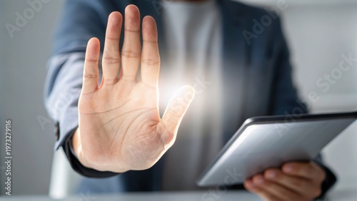 Businessman with tablet showing a glowing hand gesture symbolizing stop or control in a digital interface.
