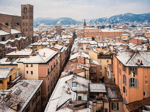 Old European city aerial view with snow covered tiled roofs on winter day, Bologna, Italy