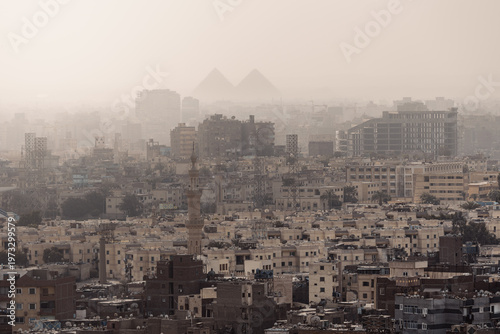 Big city panorama with boring dusty dense buildings and pyramid silhouettes in background at day, Cairo, Egypt