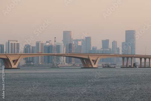 Big modern city on sea shore many skyscrapers concrete bridge in golden sunrise glow, Abu Dhabi, UAE