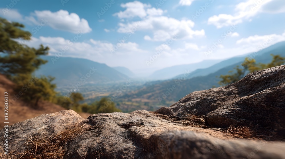 Fototapeta premium A vast mountain valley stretches out under a blue sky with clouds viewed from a rocky foreground
