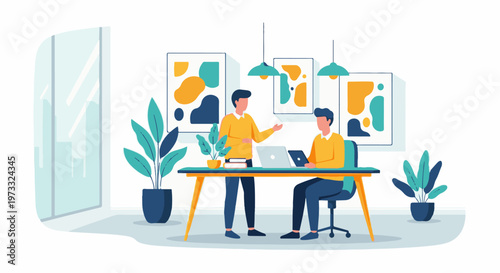 Two men collaborate at a desk with laptops and artwork