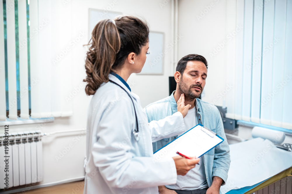 Fototapeta premium Professional female doctor checking a male patient's lymph nodes by palpating his neck. Healthcare worker with a clipboard performing a physical exam. Medical consultation and diagnosis concept.