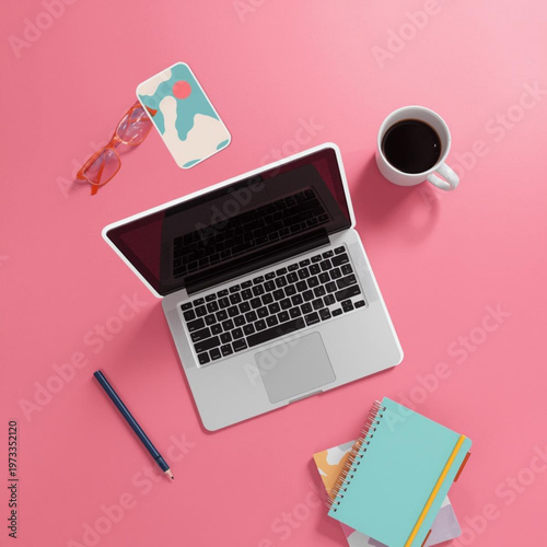 A laptop computer surrounded by office supplies on a pink background