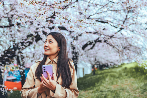 Traveler asian woman with mobile phone travel in sakura cherry blossom tree in kumagaya Saitama Japan in spring season