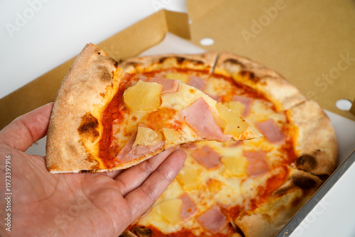 hand grabbed the Hawaiian pizza from the box.