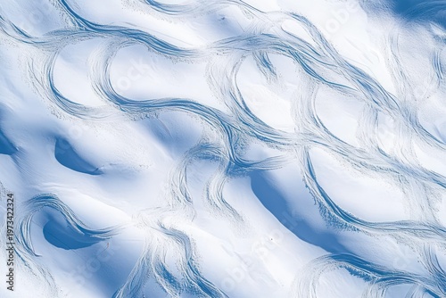 aerial view of sweeping curved ski and snowboard tracks carved into smooth powder snow with soft blue shadows conveying serene dynamic motion