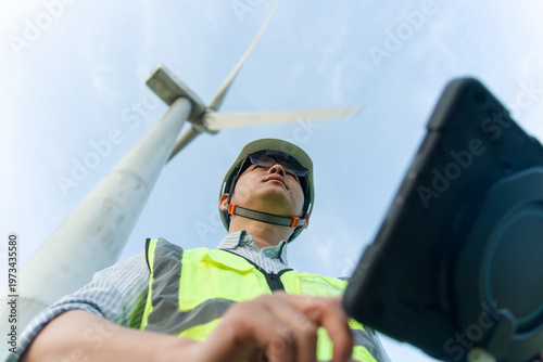 Photos Wind power engineer conducting on-site inspection of wind turbine with tablet de