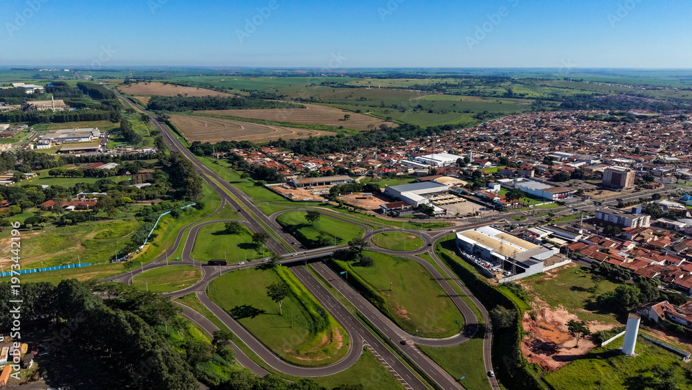 Fototapeta premium An aerial view of a city with a highway and green spaces under a clear blue sky