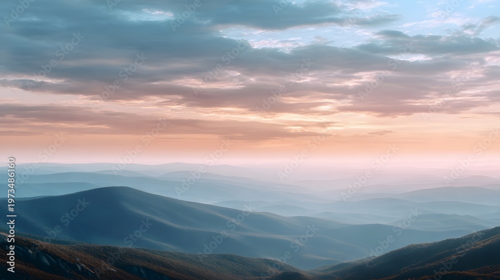 Fototapeta premium A sweeping panoramic view of receding mountain ranges under a pastel hued sunrise sky