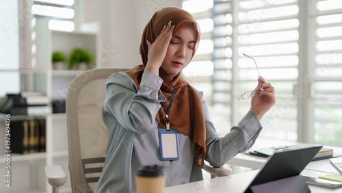 Asian adult woman office worker experiences headache eye strain fatigue burnout digital work modern home office workspace discomfort