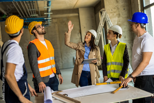Foto Female engineer pointing at ceiling pipes and explaining installation details to her construction team