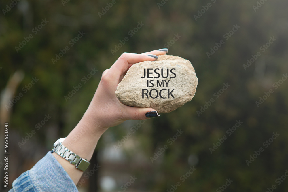 Obraz premium Female hand showing Jesus Is My Rock message on rock.