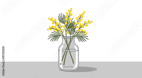 A vibrant bouquet of yellow mimosa blossoms with feathery green foliage rests gracefully inside a clear glass vase atop a minimalist grey horizontal surface.