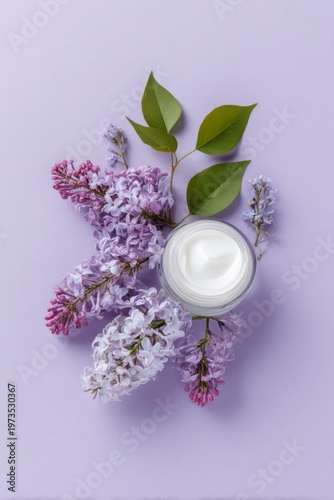 elegant cosmetic cream jar and lilac flowers on a purple background