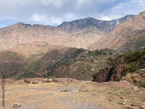 A wide landscape shot showing the barren and rugged mountain peaks of Baboon Valley under a cloudy sky.