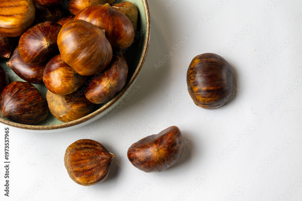 Obraz premium Chestnuts in bowl on white background with copy space