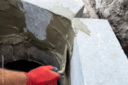 Worker applying mortar to concrete blocks for septic tank
