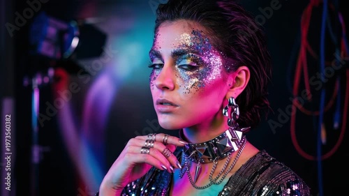 A model shows a unique look with bright makeup and sparkly clothes in a studio filled with lights