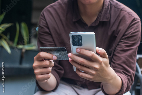 Foto Man holding credit card and smartphone for online payment, illustrating fintech,
