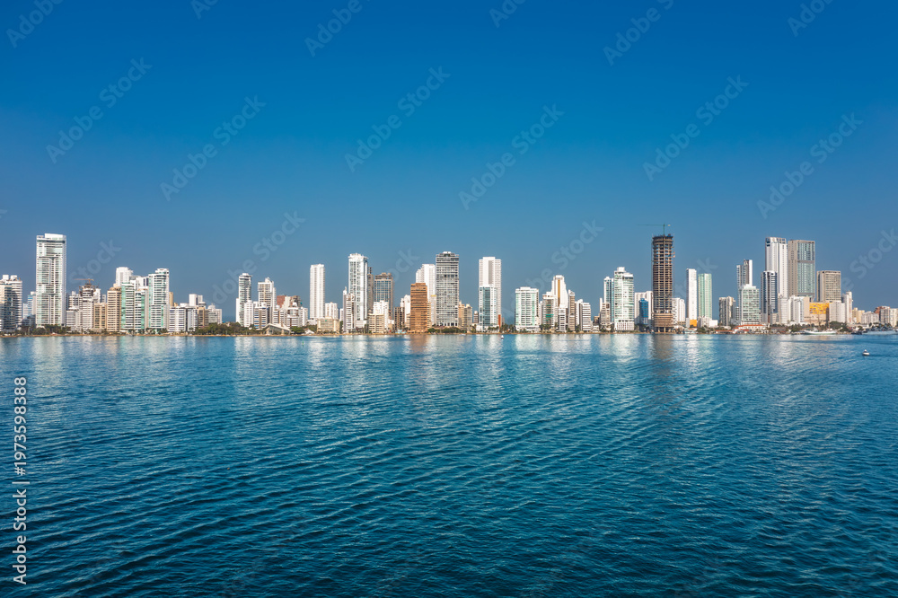Obraz premium Panoramic view of the Cartagena skyline and Bocagrande district with modern skyscrapers reflecting on the water under a blue sky, Colombia