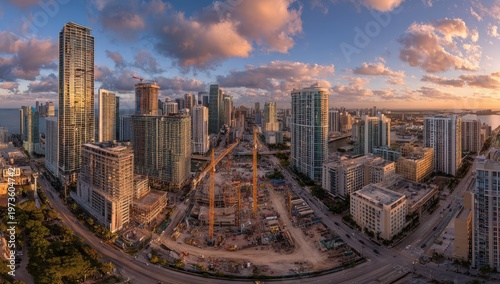 Panoramic Aerial View of Miami Skyline at Sunset with Construction Cranes.