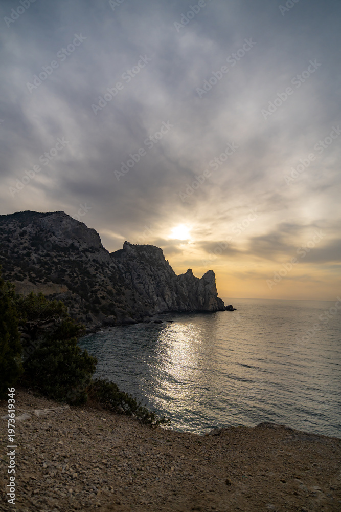 Fototapeta premium Seascape sunset rocks dramatic golden light reflecting on the water along the mountainous coastline