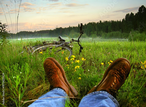 Foto A first-person perspective of a traveler resting in a green meadow during a long-distance cycling trip through the Masurian District