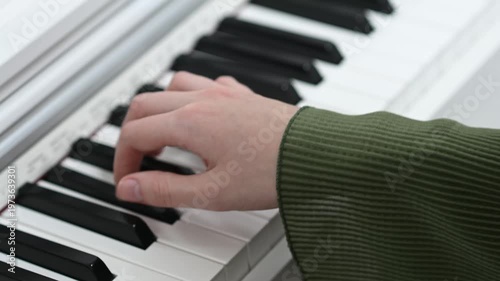 female pianist hands on black and white synthesizer keyboard, close-up view, young woman playing piano, professional musician