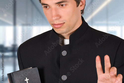 Картината върху платно Young man in black clerical attire holds Bible
