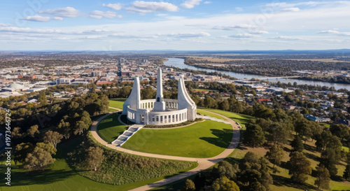 An aerial view showcases the majestic Australian War Memorial situated on Mount Ainslie, overlooking Canberra's vast cityscape and the scenic Molonglo River under a clear sky.