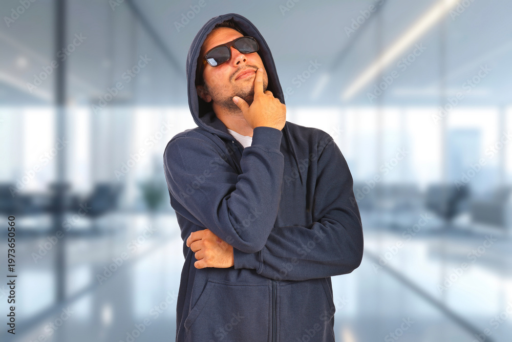 Fototapeta premium Man in hoodie and sunglasses appears thoughtful