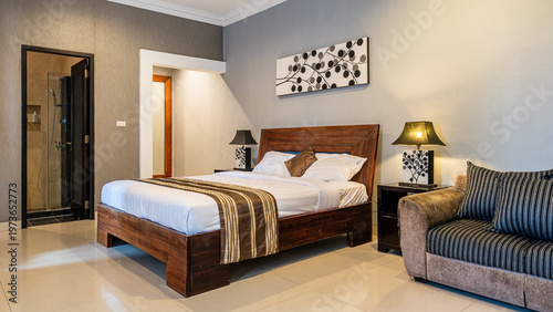A bedroom with a bed, a couch, and a lamp. The bed is made and the room is clean and tidy.