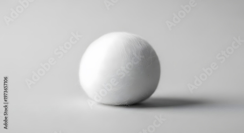 A single white egg rests on a neutral gray surface