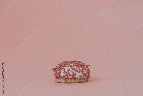 Dessert petit four with pink sprinkles on a pink background. Festive treat. Shortbread. Dessert with copy space. Sweet food for coffee. Exquisite mini cake. Fast carbohydrates. Diet violation.