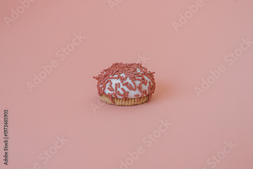 Dessert petit four with pink sprinkles on a pink background. Festive treat. Shortbread. Dessert with copy space. Sweet food for coffee. Exquisite mini cake. Fast carbohydrates. Diet violation.