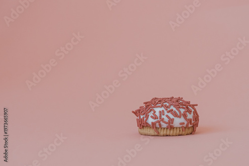 Dessert petit four with pink sprinkles on a pink background. Festive treat. Shortbread. Dessert with copy space. Sweet food for coffee. Exquisite mini cake. Fast carbohydrates. Diet violation.