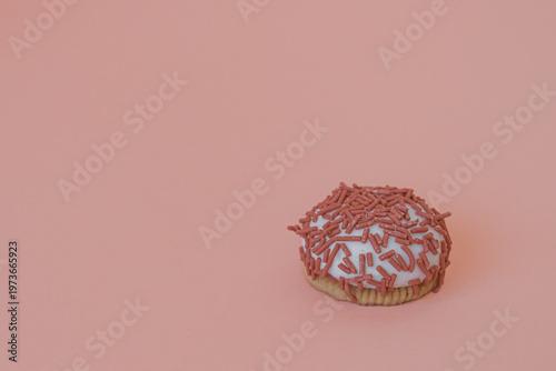 Dessert petit four with pink sprinkles on a pink background. Festive treat. Shortbread. Dessert with copy space. Sweet food for coffee. Exquisite mini cake. Fast carbohydrates. Diet violation.