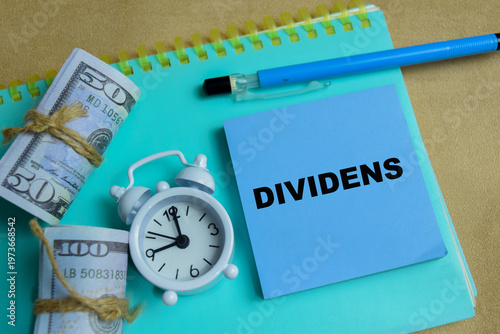 Concept of dividends write on sticky notes isolated on Wooden Table. For passive income and time value of money