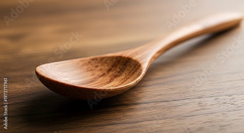 A close-up of a simple, handcrafted wooden spoon resting on a textured wooden surface
