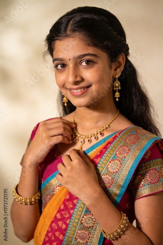 Smiling young Indian girl in traditional saree and gold jewelry