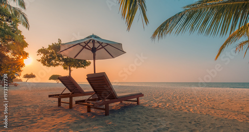 Gorgeous romantic sunset beach with elegant white sunbeds and palm leaf umbrella, breathtaking calm tropical ocean view, radiant golden sky and captivating luxury honeymoon summer vacation background