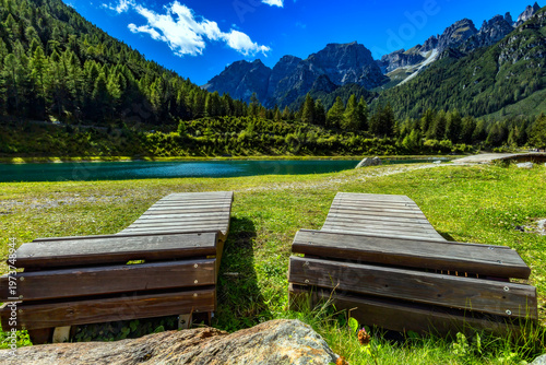 Wooden loungers by a mountain lake with alpine panorama