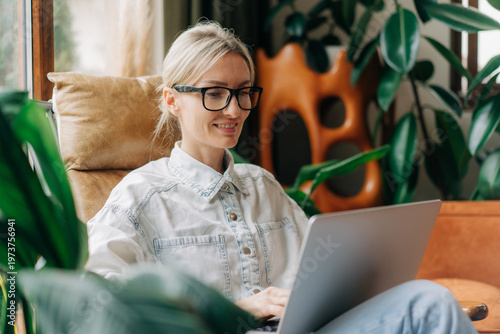 Happy smiling blonde woman using a laptop to work remotely.