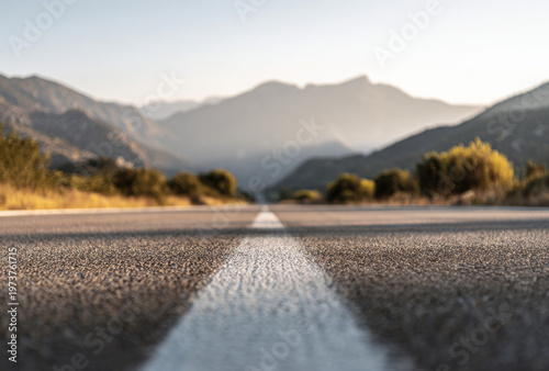 Low-angle close-up of a textured asphalt road with white dividing line in sharp focus