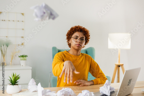 Start up business concept. Sad African business woman writing document crumpled paper and tossed it. Proposed project failed. Tired overworked girl no idea sitting at workplace writing notes at office